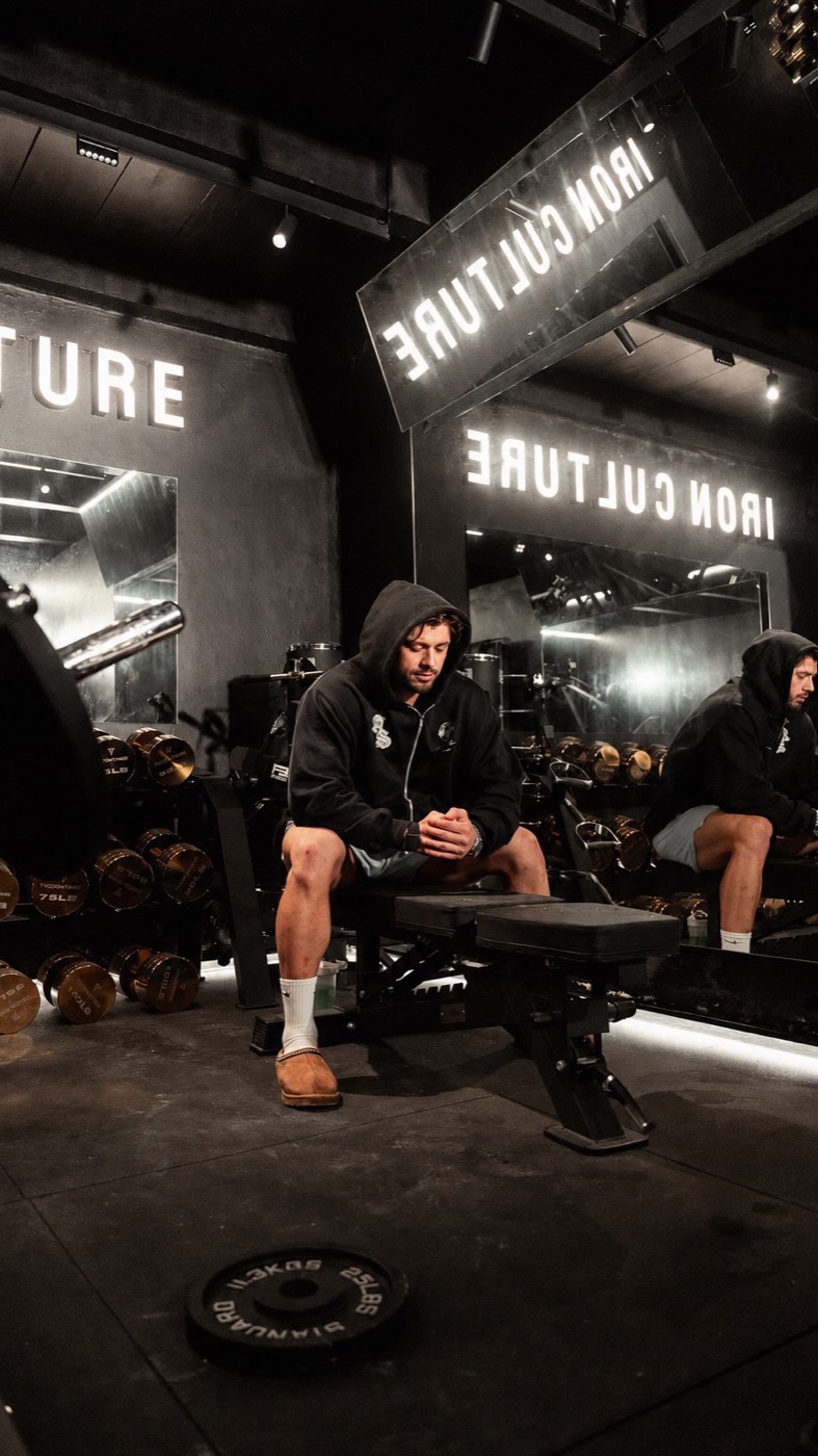 Grupo de atletas con sudadera Iron Culture entre estaciones de entrenamiento